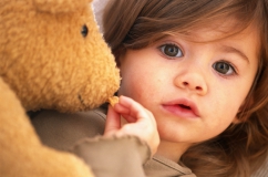 Une petite fille qui arrache un morceau d'un ours en peluche
