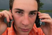 un jeune homme avec deux téléphones portables
