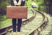 voyageuse attendant sur les rails, une valise à la main