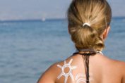une fillette devant l'océan, crème solaire sur l'épaule