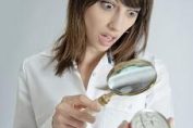 Une femme lit l'étiquette d'un produit avec une loupe