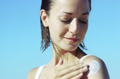 Une femme se met de la crème solaire sur l'épaule