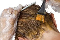 Une femme avec un pinceau enduit de teintures dans les cheveux