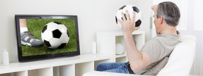 homme devant un match de foot à la télé, avec un ballon à la main