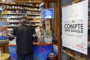 client d'un buraliste à côté d'une affichette “Ouvrez ici votre compte sans banque”
