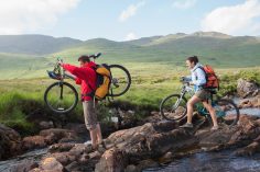 Un couple avec deux VTT traverse une rivière en montagne