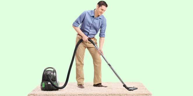 homme aspirant un tapis
