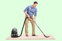 homme aspirant un tapis