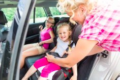 personne attachant un enfant dans une voiture