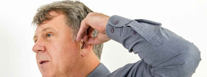 homme réglant son appareil auditif