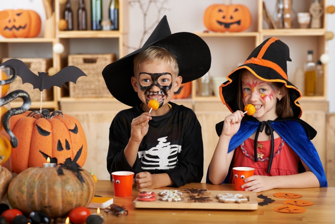 Deux enfants déguisés pour halloween portent des sucettes en forme de citrouilles à leur bouche