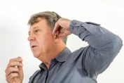 homme réglant son appareil auditif