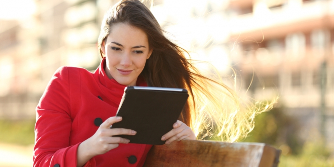 Une femme regarde sa tablette en extérieur