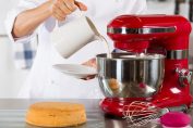 Un homme verse du lait dans le bol d'un robot pâtissier