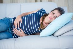 Une femme victime d'une douleur au ventre est couchée sur un canapé