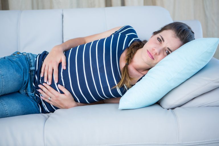 Une femme victime d'une douleur au ventre est couchée sur un canapé