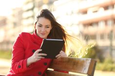Une femme lit sur sa tablette en extérieur