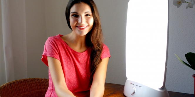 Une femme à côté d'une lampe de luminothérapie