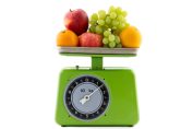 Deux pommes, deux oranges et une grappr de raisin sur une balance