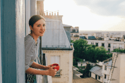 Une jeune femme à la fenête de son immeuble