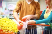 Un couple remplit un sac plastique de citrons au supermarché