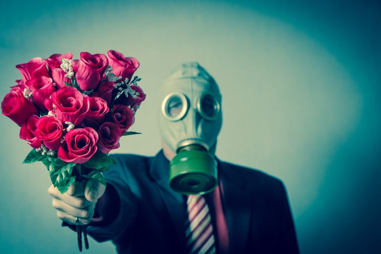 homme tenant des roses et portant un masque à gaz