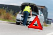 un automobiliste en panne sur la route, avec un triangle rouge de signalisation