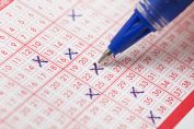 Un stylo en train de cocher des numéros sur une grille de loto