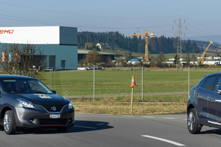 Deux suzuki Baleno – une essence, une hybride – roulent sur un circuit automobile