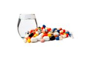 dizaines de gélules et pilules à côté d'un verre d'eau