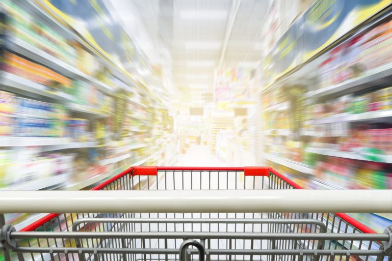 Un caddy file dans les rayons d'un supermarché