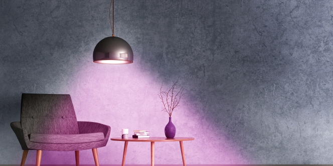 Une pièce - table basse, fauteuil - est baignée dans une lumière douce 