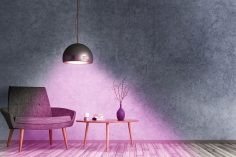Une pièce - table basse, fauteuil - est baignée dans une lumière douce