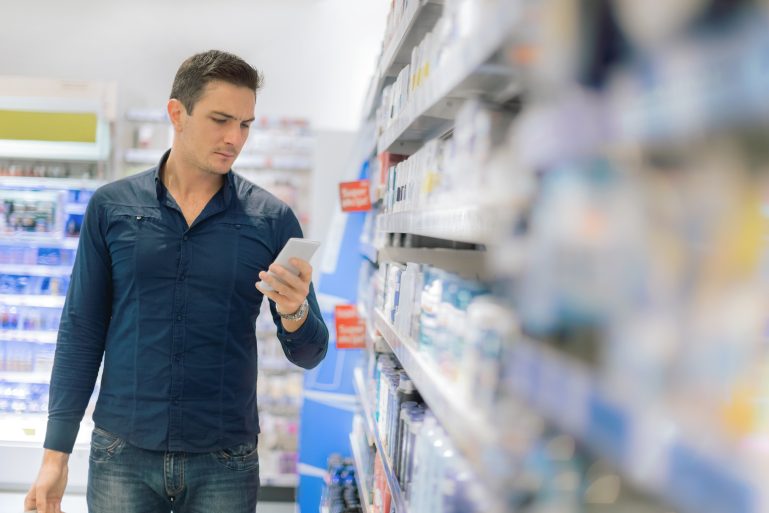 Un homme dans un supermarché regarde son smartphone