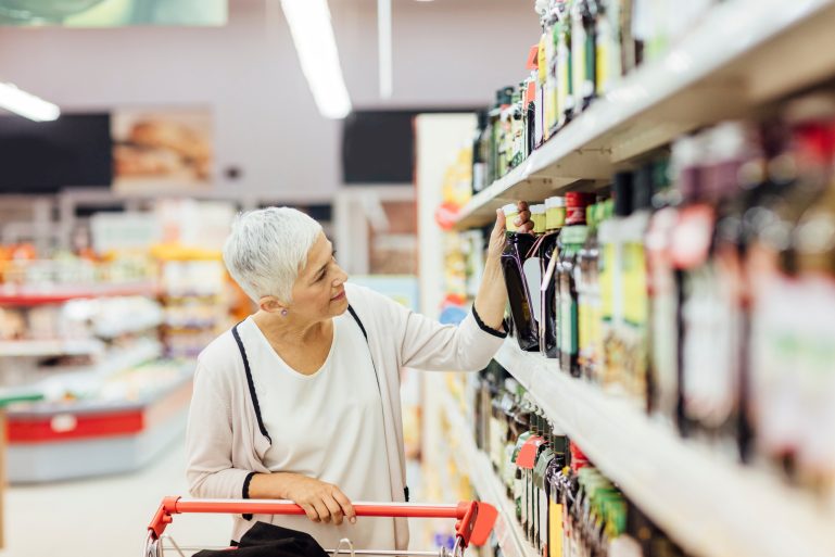 Une femme choisit une huile d'olive dans un supermarché