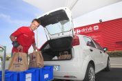 Un préparateur-livreur charge les commandes dans le coffre d'une voiture