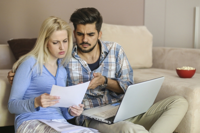 Un couple étudie des offres imprimées de comparateurs d'assurances