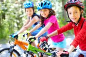 Trois enfants sur leur vélo coiffés d'un casque.