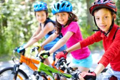 Trois enfants sur leur vélo coiffés d'un casque.