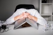 Un homme la tête sous son ordinateur portable