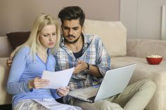 Un couple étudie des offres imprimées de comparateurs d'assurances