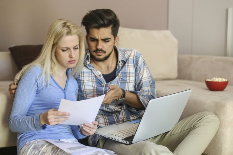 Un couple étudie des offres imprimées de comparateurs d'assurances