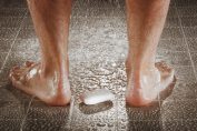 Gros plan d'un savon aux pieds d'un homme sous la douche