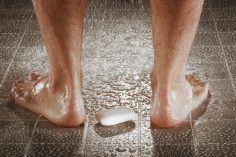 Gros plan d'un savon aux pieds d'un homme sous la douche