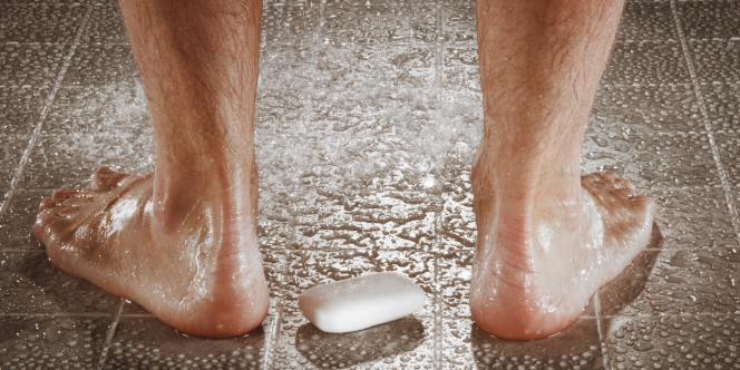 Gros plan d'un savon aux pieds d'un homme sous la douche