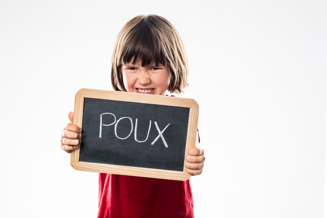 Petite fille avec le mot "pou" écrit sur une ardoise