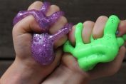Deux poings d'enfant qui serrent de la pâte slime