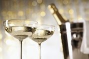 Deux coupes de champagne en gros plan, derrière, une bouteille émerge d'un seau à glace.