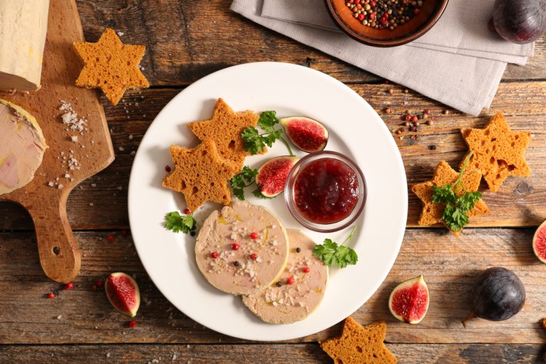 Une assiette festive de foie gras avec confiture d'oignons, figues et pain d'épice coupé en étoiles.