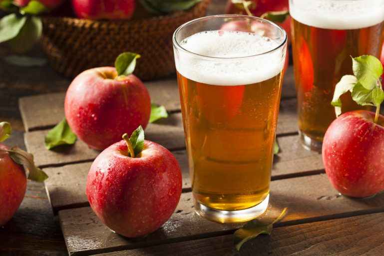 Verre de cidre avec des pommes rouges sur une table en bois